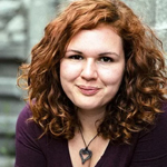 a woman with curly red hair smiling, labeled as Book Aficionado